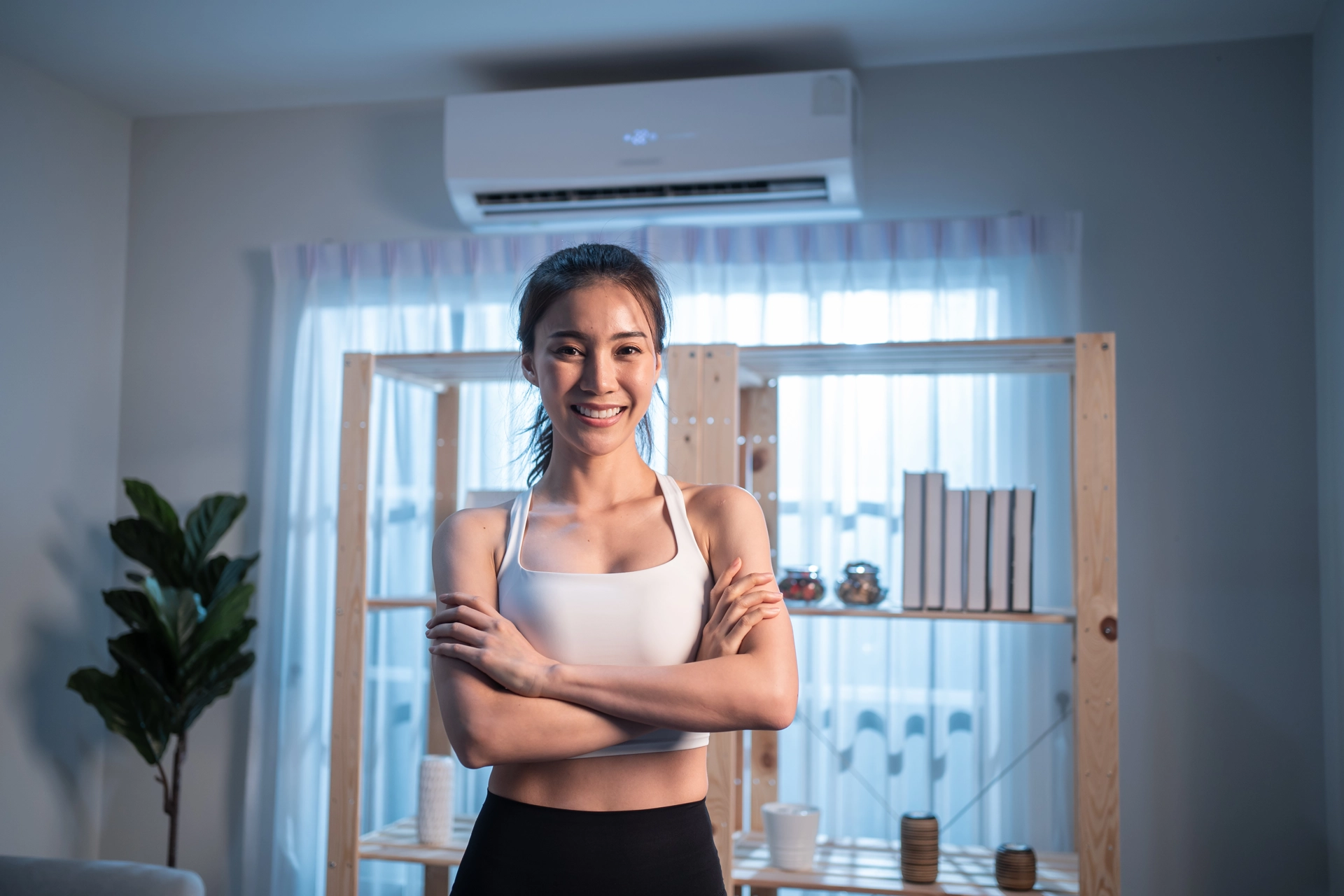 Woman smiling in a room with a ductless HVAC system on the wall.