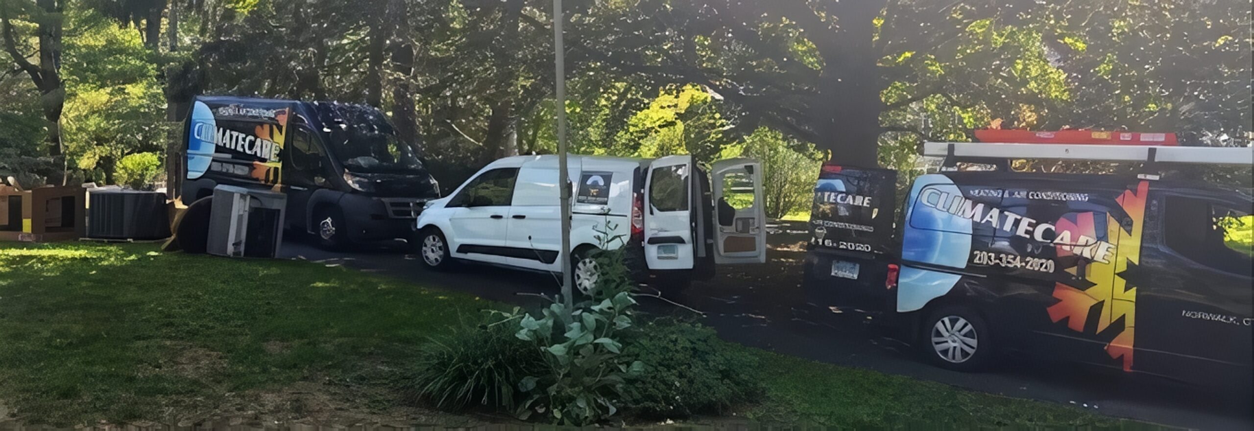 Climate Care mobile service vehicles parked in a green outdoor area.