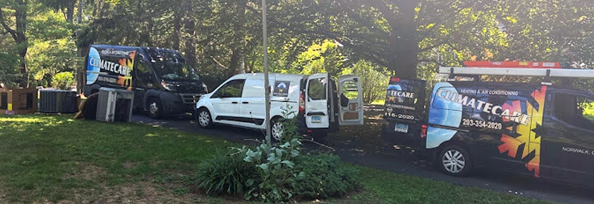 Multiple service vans parked in a green residential area for HVAC installation.