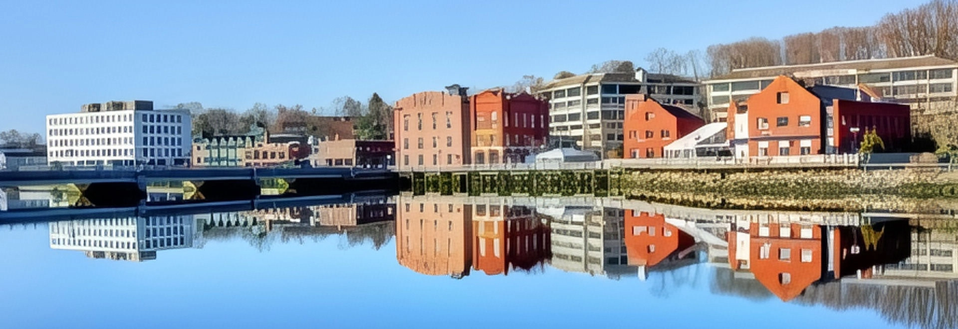 Serene view of Westport Town reflecting on calm water with historical buildings.