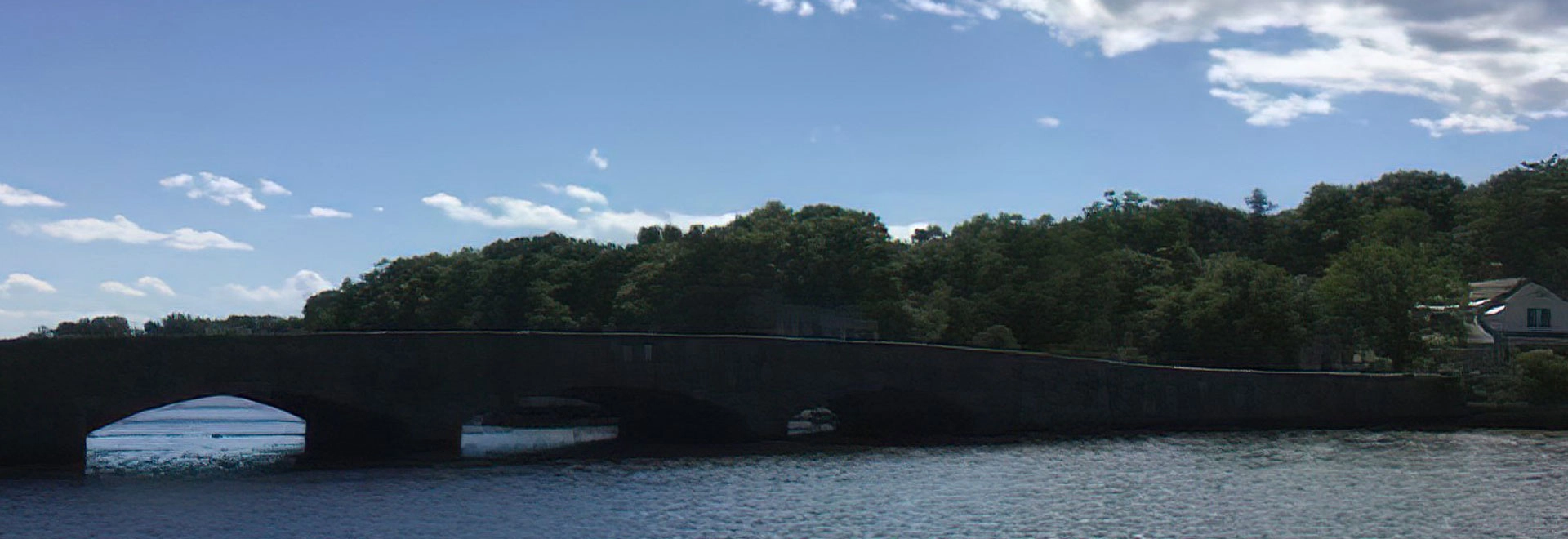 Scenic view of a stone bridge over calm water in Darien, Connecticut during summer.