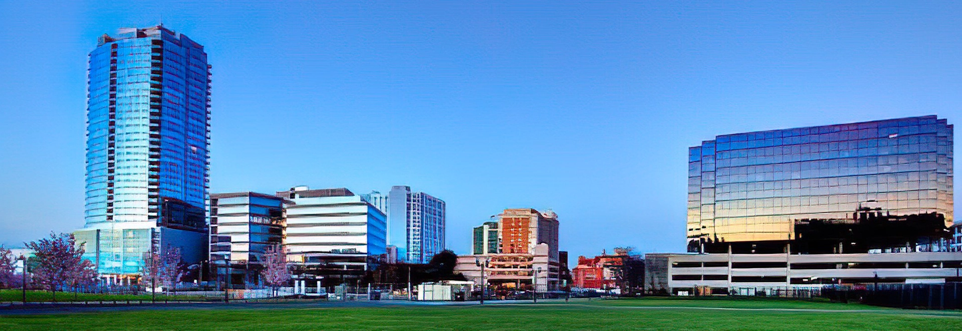 Skyline of Downtown Stamford, CT at dusk featuring modern skyscrapers and green space.