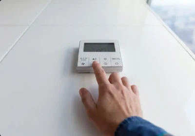 Hand adjusting a modern thermostat displaying temperature settings.